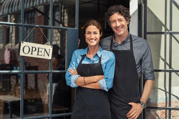 a man and a woman standing in front of their restaurant