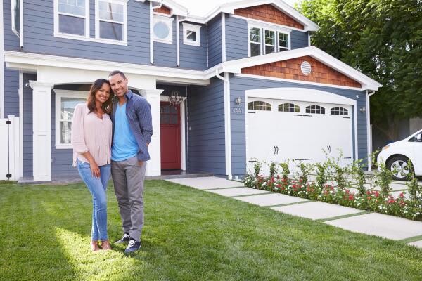 a couple standing in front of their house